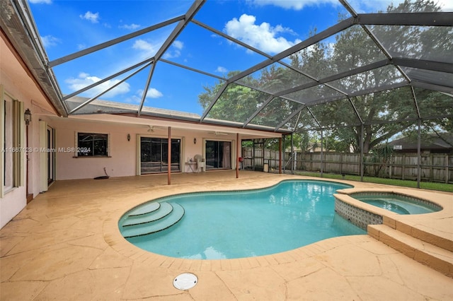 view of pool with a patio, glass enclosure, and an in ground hot tub