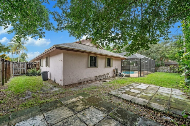 rear view of property with a lanai, a patio, a fenced in pool, and a lawn