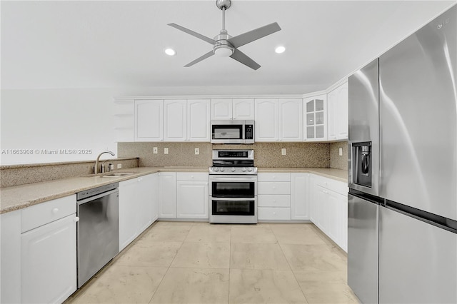 kitchen featuring decorative backsplash, appliances with stainless steel finishes, ceiling fan, sink, and white cabinetry