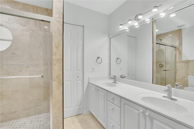 bathroom featuring tile patterned floors, vanity, a shower with shower door, and toilet