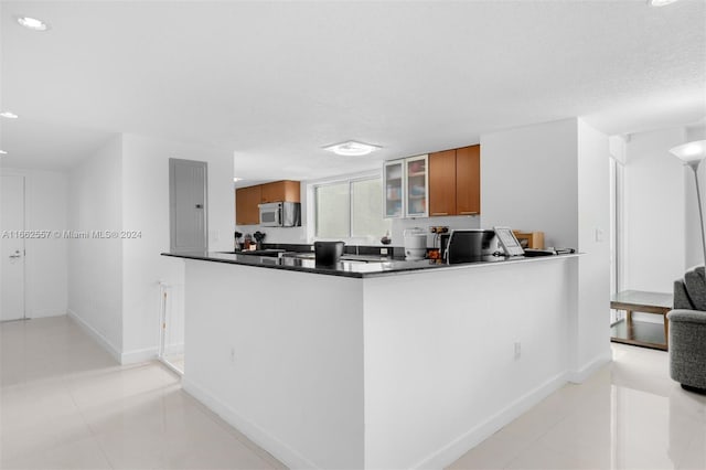 kitchen with kitchen peninsula, electric panel, light tile patterned floors, and a textured ceiling