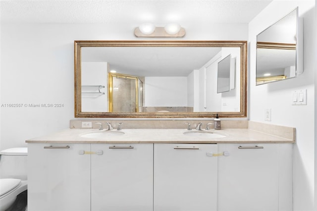 bathroom featuring a textured ceiling, vanity, toilet, and a shower with door