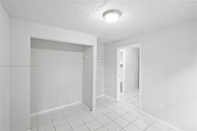 empty room featuring a textured ceiling and light tile patterned floors