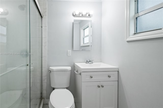 bathroom featuring vanity, a shower with shower door, and toilet