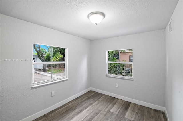 unfurnished room featuring a textured ceiling, hardwood / wood-style floors, and a wealth of natural light