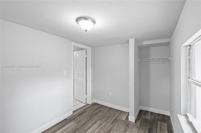 unfurnished bedroom with a textured ceiling, dark hardwood / wood-style floors, and a closet