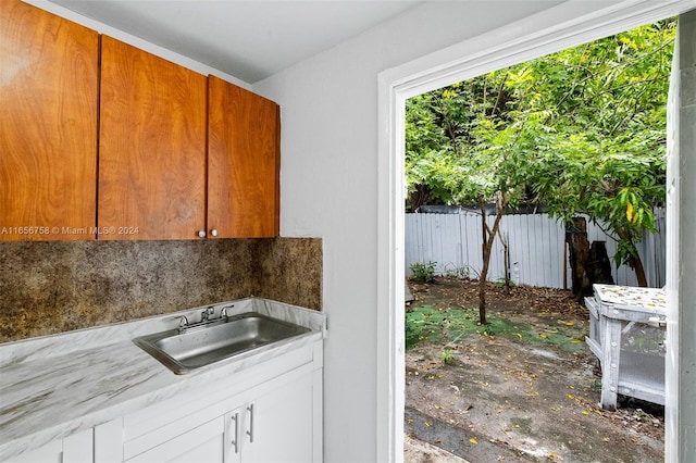 kitchen with backsplash, white cabinetry, and sink