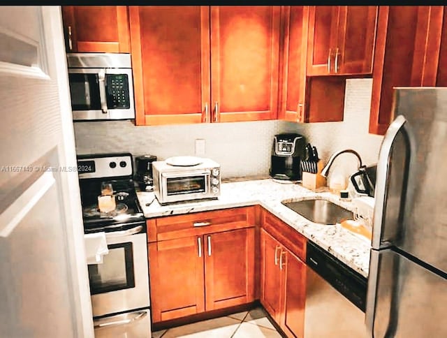 kitchen featuring light stone countertops, decorative backsplash, sink, and stainless steel appliances