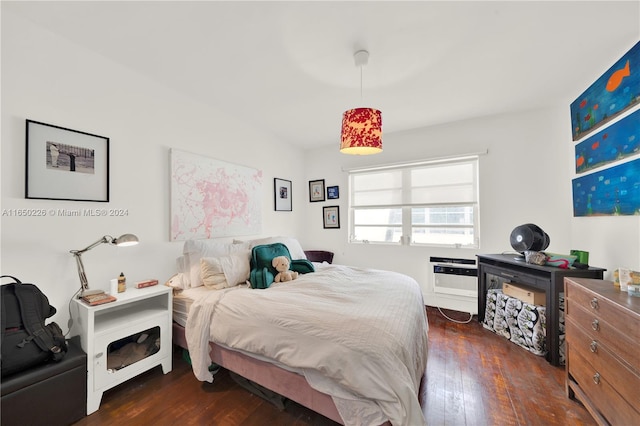 bedroom with an AC wall unit and dark hardwood / wood-style floors