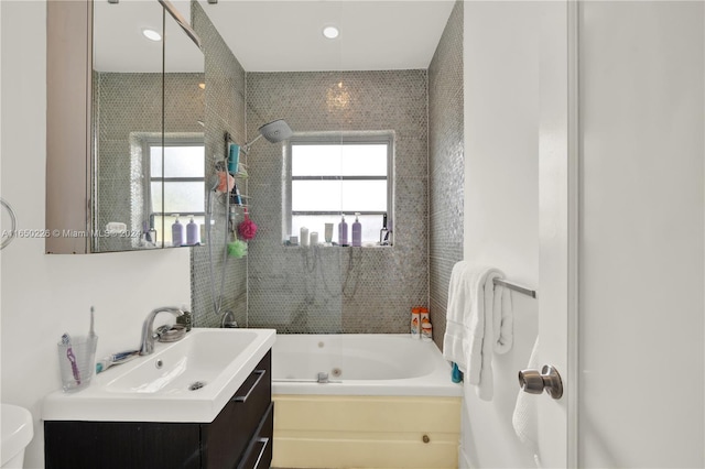 full bathroom featuring tiled shower / bath, vanity, and toilet