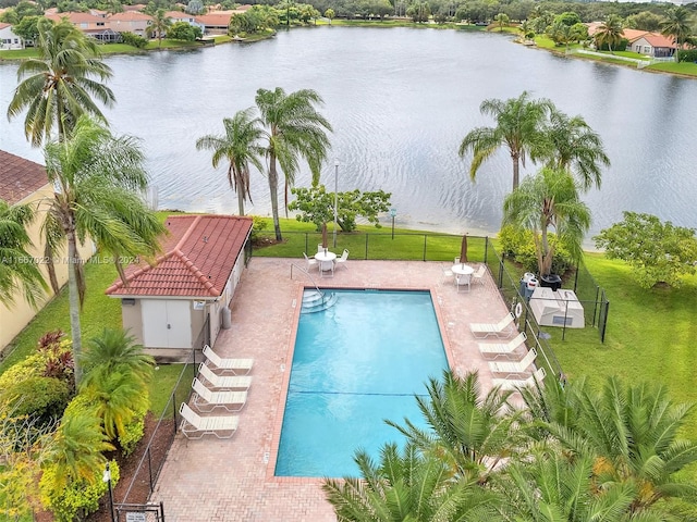 view of swimming pool featuring a lawn, a water view, a patio area, and an outbuilding