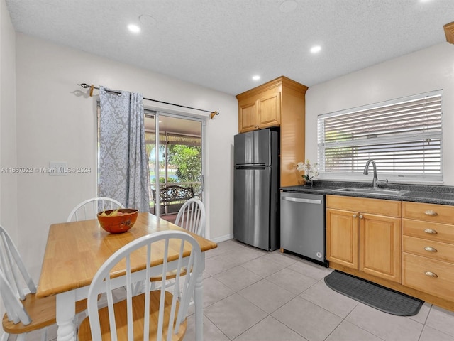 kitchen with light tile patterned floors, sink, a textured ceiling, stainless steel appliances, and dark stone counters