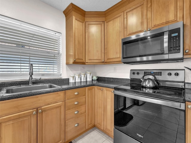 kitchen featuring a textured ceiling, sink, light tile patterned floors, and stainless steel appliances