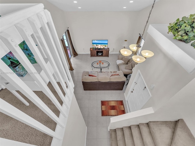 stairway with a high ceiling, tile patterned flooring, and an inviting chandelier