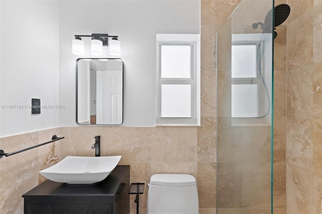 bathroom featuring tiled shower, vanity, toilet, and tile walls