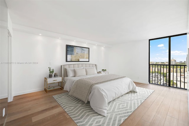 bedroom featuring expansive windows, light hardwood / wood-style floors, and access to exterior