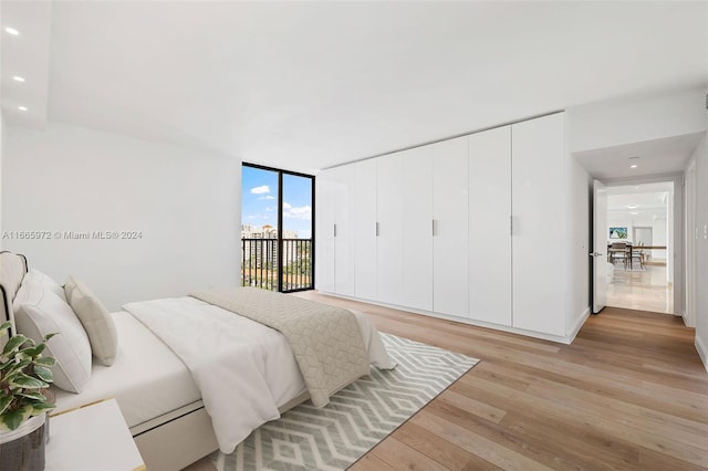 bedroom featuring access to exterior, floor to ceiling windows, and light wood-type flooring