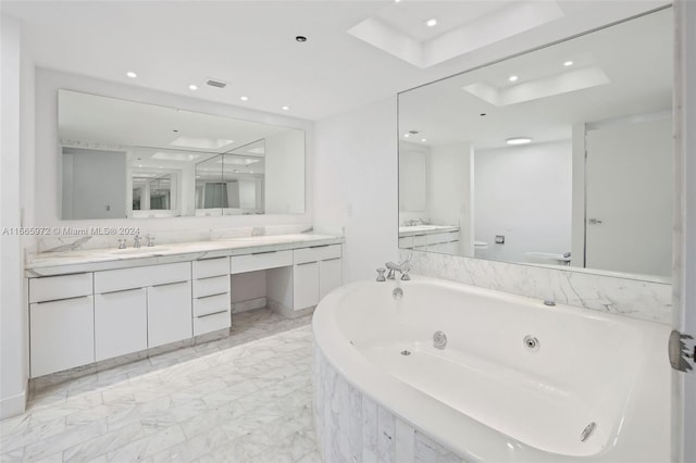 bathroom with vanity, tiled tub, and toilet