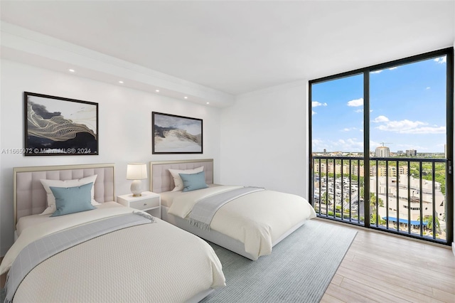 bedroom with access to outside, expansive windows, light hardwood / wood-style floors, and multiple windows