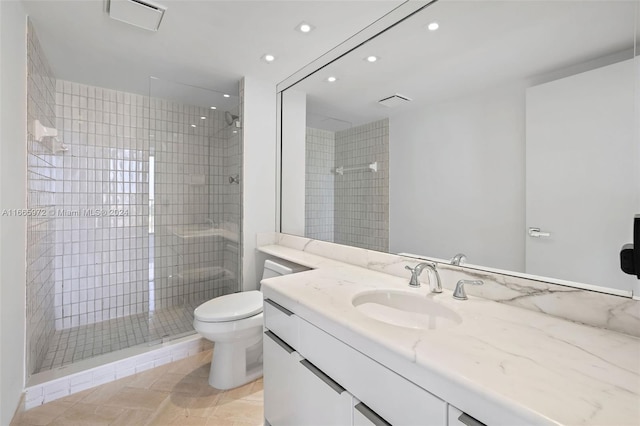 bathroom with tile patterned floors, vanity, tiled shower, and toilet