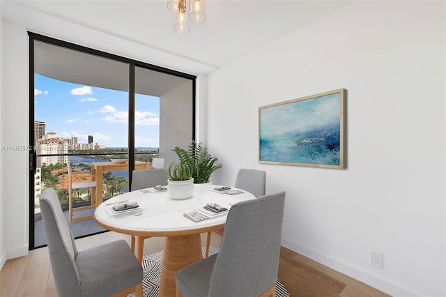 dining space featuring light wood-type flooring, plenty of natural light, floor to ceiling windows, and a chandelier