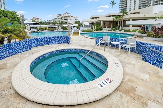 view of swimming pool featuring a patio and a hot tub