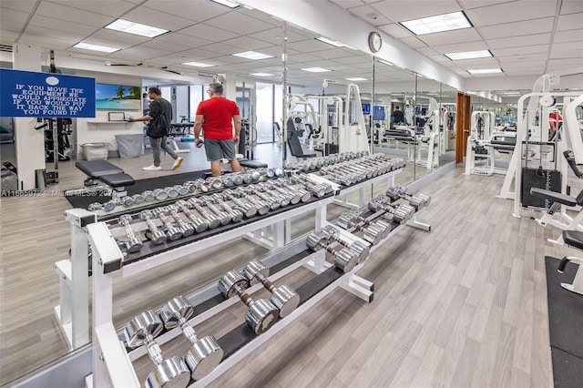 exercise room with a paneled ceiling and light hardwood / wood-style floors