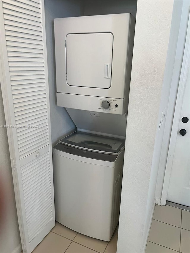 clothes washing area with stacked washer / drying machine and light tile patterned floors