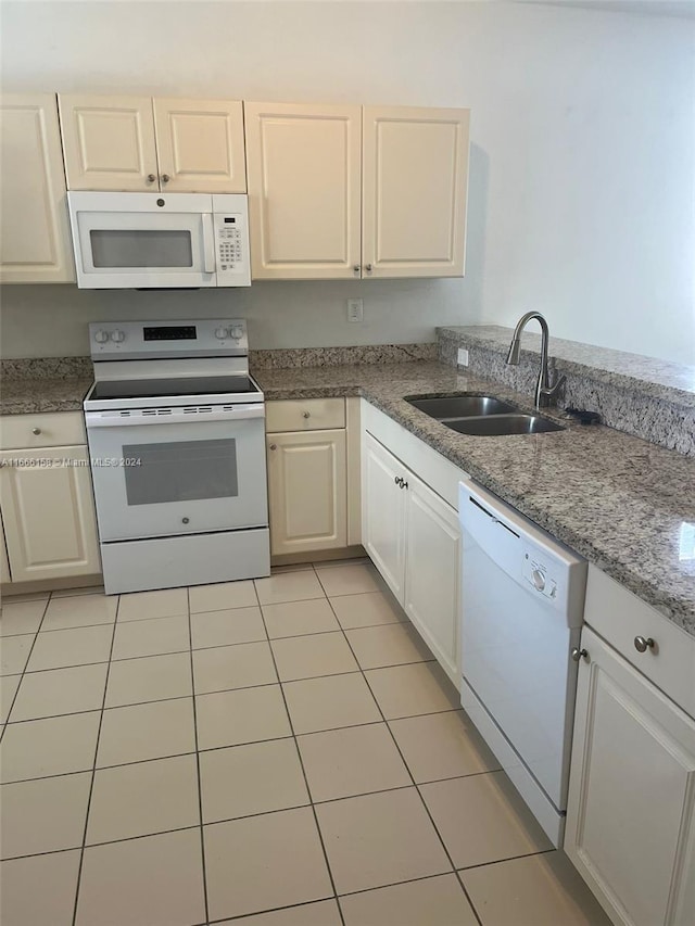 kitchen with white appliances, white cabinetry, sink, and light tile patterned floors