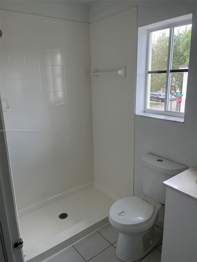 bathroom with a tile shower, tile patterned flooring, vanity, and toilet