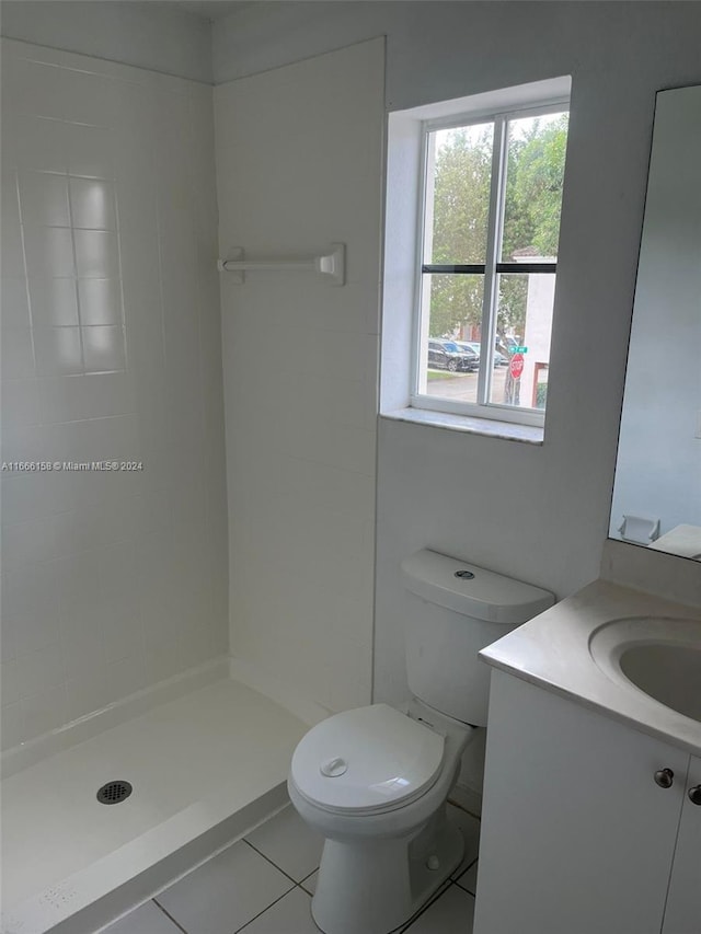 bathroom with tile patterned flooring, walk in shower, vanity, and toilet