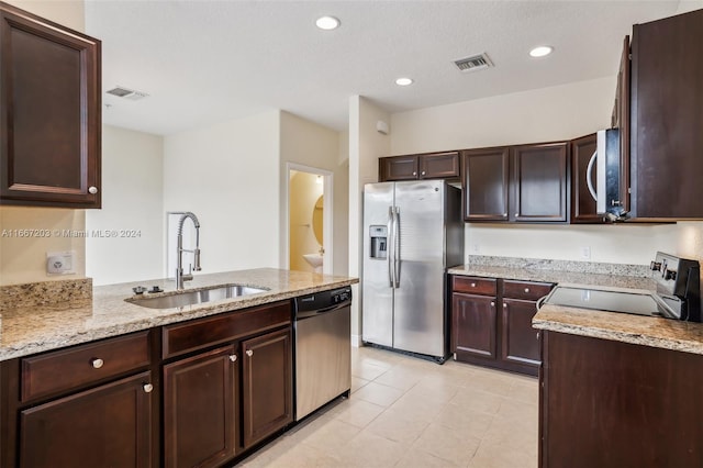 kitchen with light stone counters, a textured ceiling, sink, stainless steel appliances, and dark brown cabinetry