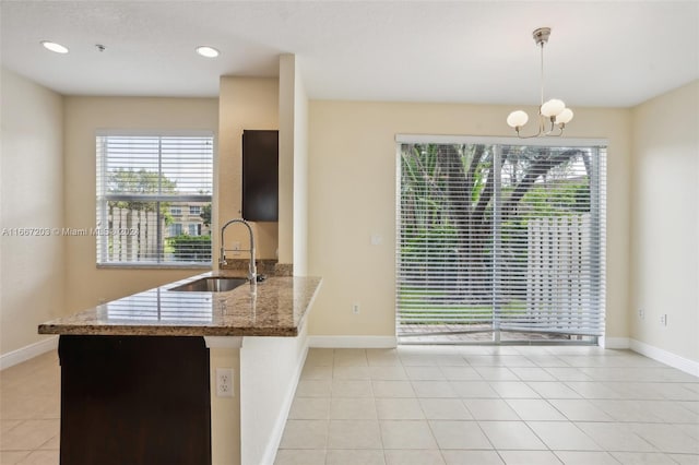 kitchen featuring light stone counters, pendant lighting, light tile patterned floors, sink, and kitchen peninsula