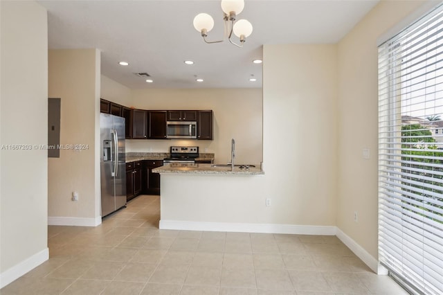 kitchen with light stone counters, dark brown cabinetry, light tile patterned flooring, stainless steel appliances, and a notable chandelier