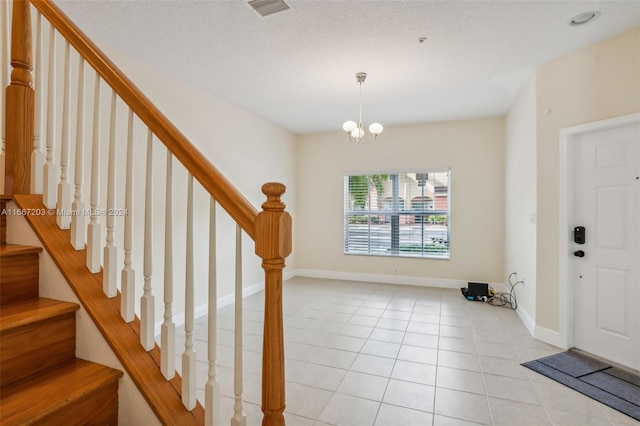 tiled foyer with a notable chandelier and a textured ceiling