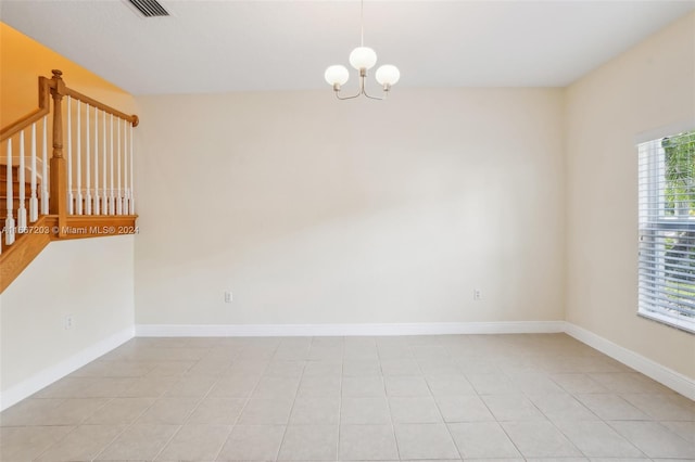 tiled spare room featuring a notable chandelier