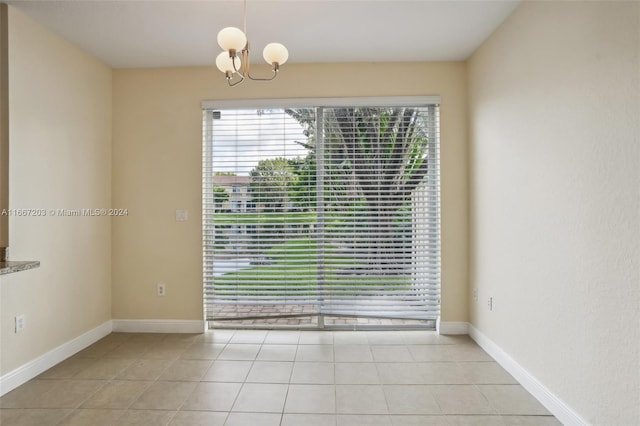 tiled empty room featuring a chandelier