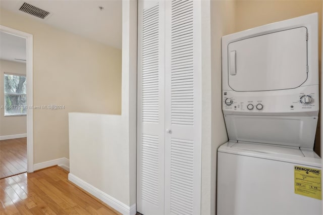 laundry room featuring stacked washer and clothes dryer and light hardwood / wood-style flooring