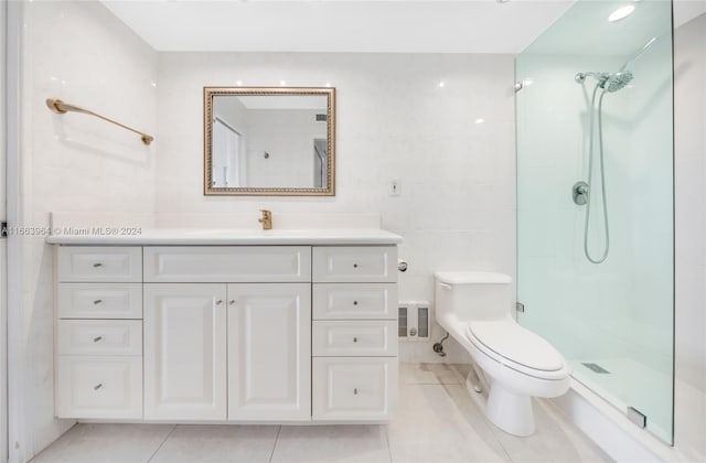 bathroom with tile walls, a shower, tile patterned floors, vanity, and toilet