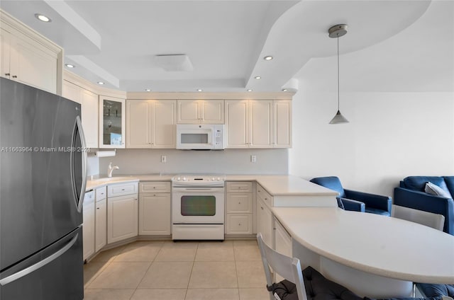 kitchen featuring hanging light fixtures, light tile patterned floors, white appliances, cream cabinets, and a breakfast bar