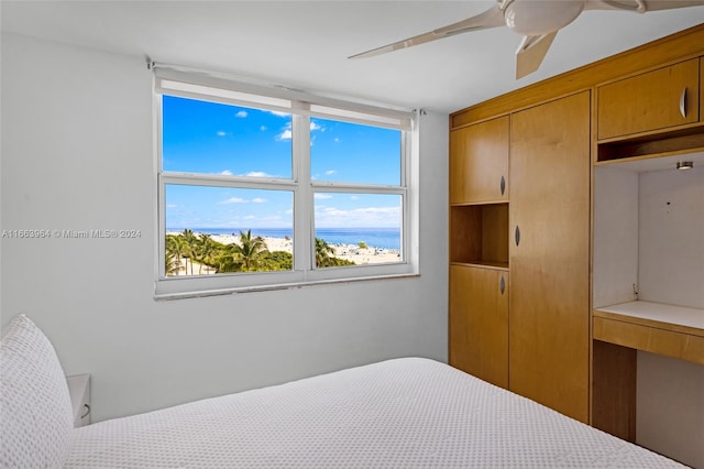 bedroom with a water view and ceiling fan