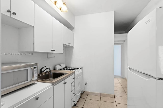 kitchen with white cabinets, sink, light tile patterned floors, and white appliances