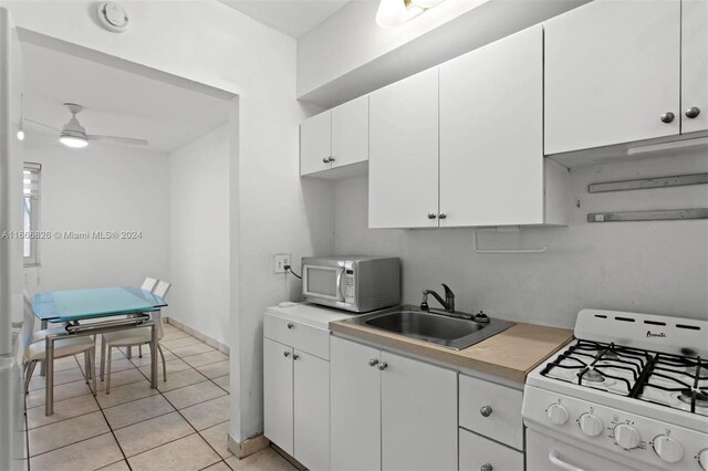 kitchen featuring white cabinetry, light tile patterned flooring, white appliances, ceiling fan, and sink