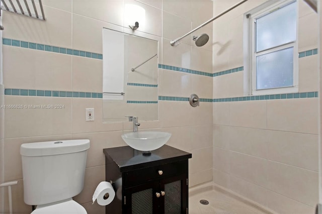 bathroom featuring tile walls, tiled shower, vanity, and toilet