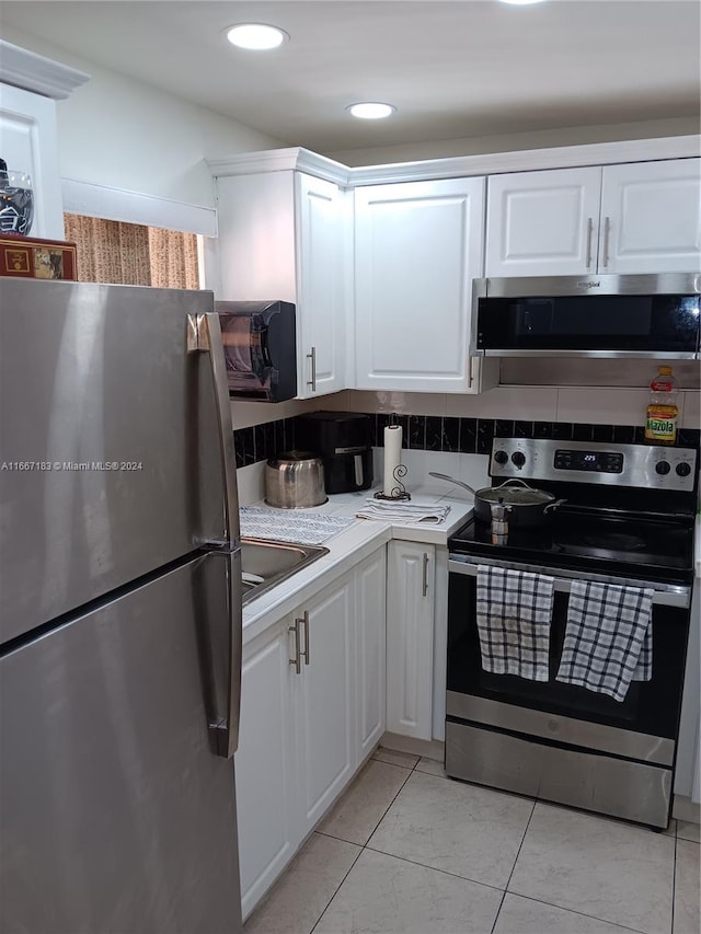 kitchen featuring white cabinets, stainless steel appliances, backsplash, and sink