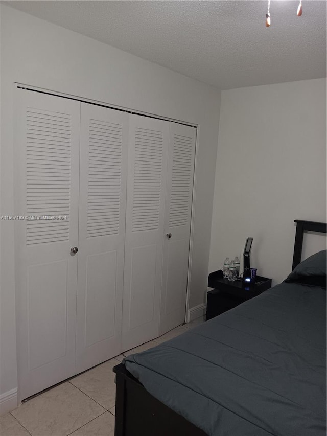 tiled bedroom featuring a textured ceiling and a closet