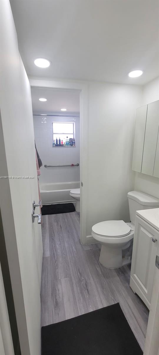 full bathroom with vanity, shower / bath combination, toilet, and hardwood / wood-style flooring