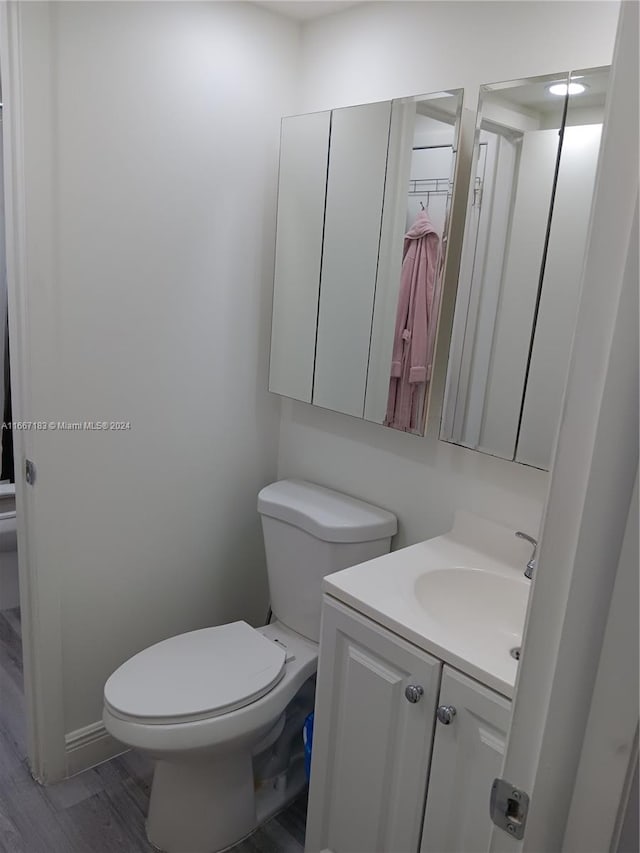 bathroom with hardwood / wood-style floors, vanity, and toilet