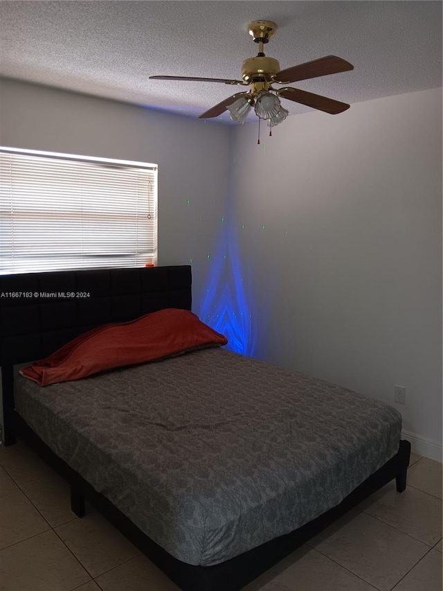 tiled bedroom featuring ceiling fan and a textured ceiling