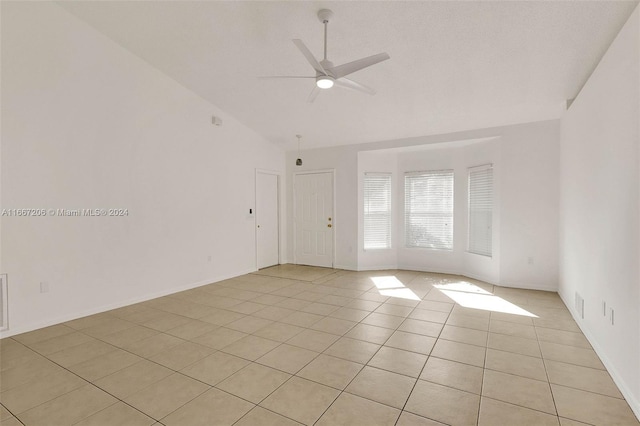 spare room with vaulted ceiling, ceiling fan, and light tile patterned floors